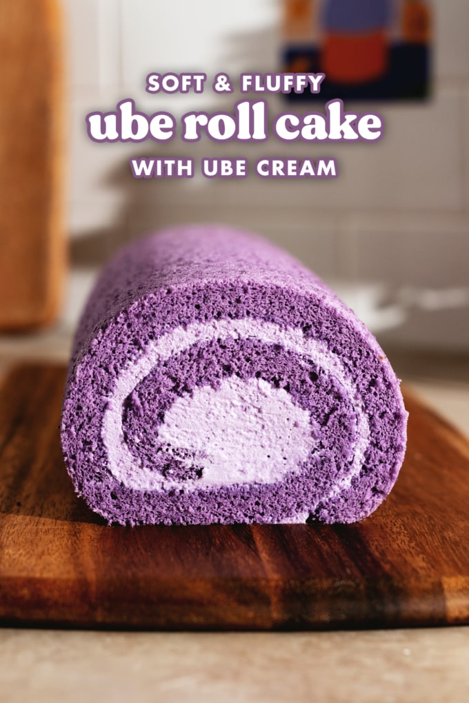 Cross section view of a purple ube roll cake on a wooden board.