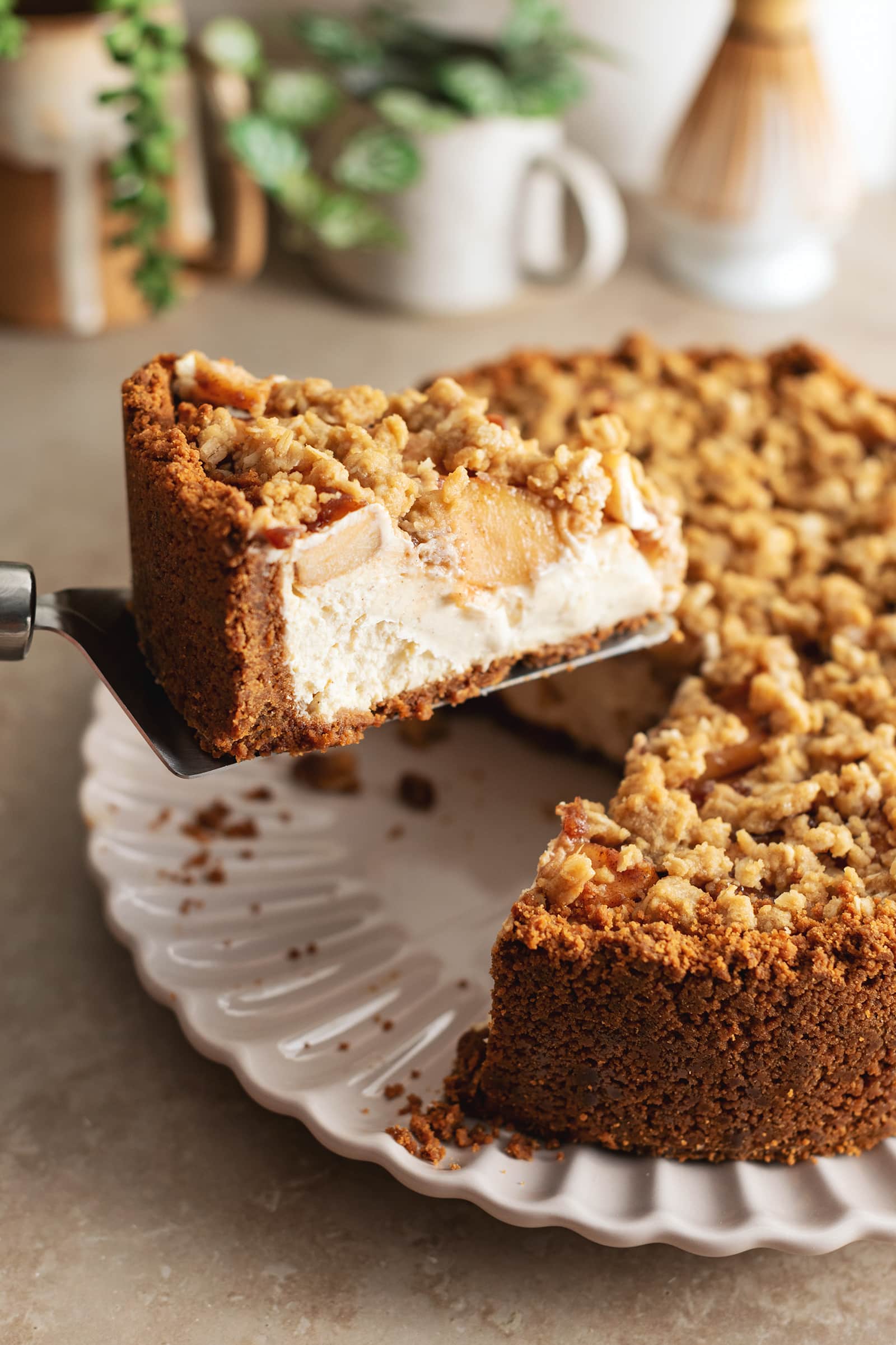 A slice of apple crumble cheesecake lifted up with a cake server.