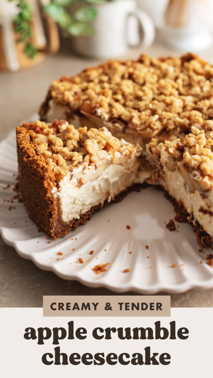 A slice of apple crumble cheesecake cut from the rest of the cake on a serving plate.