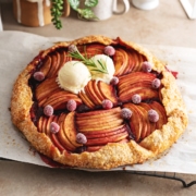 A cranberry apple galette sitting on a wire rack on a kitchen counter.