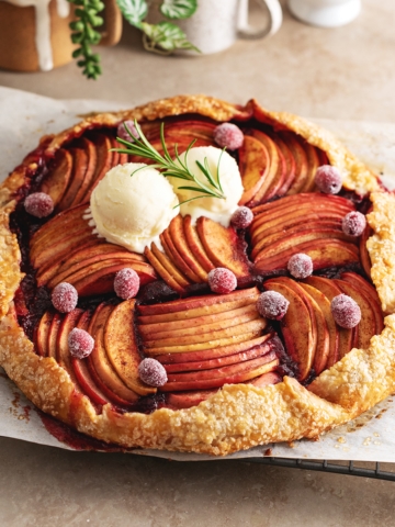 A cranberry apple galette sitting on a wire rack on a kitchen counter.