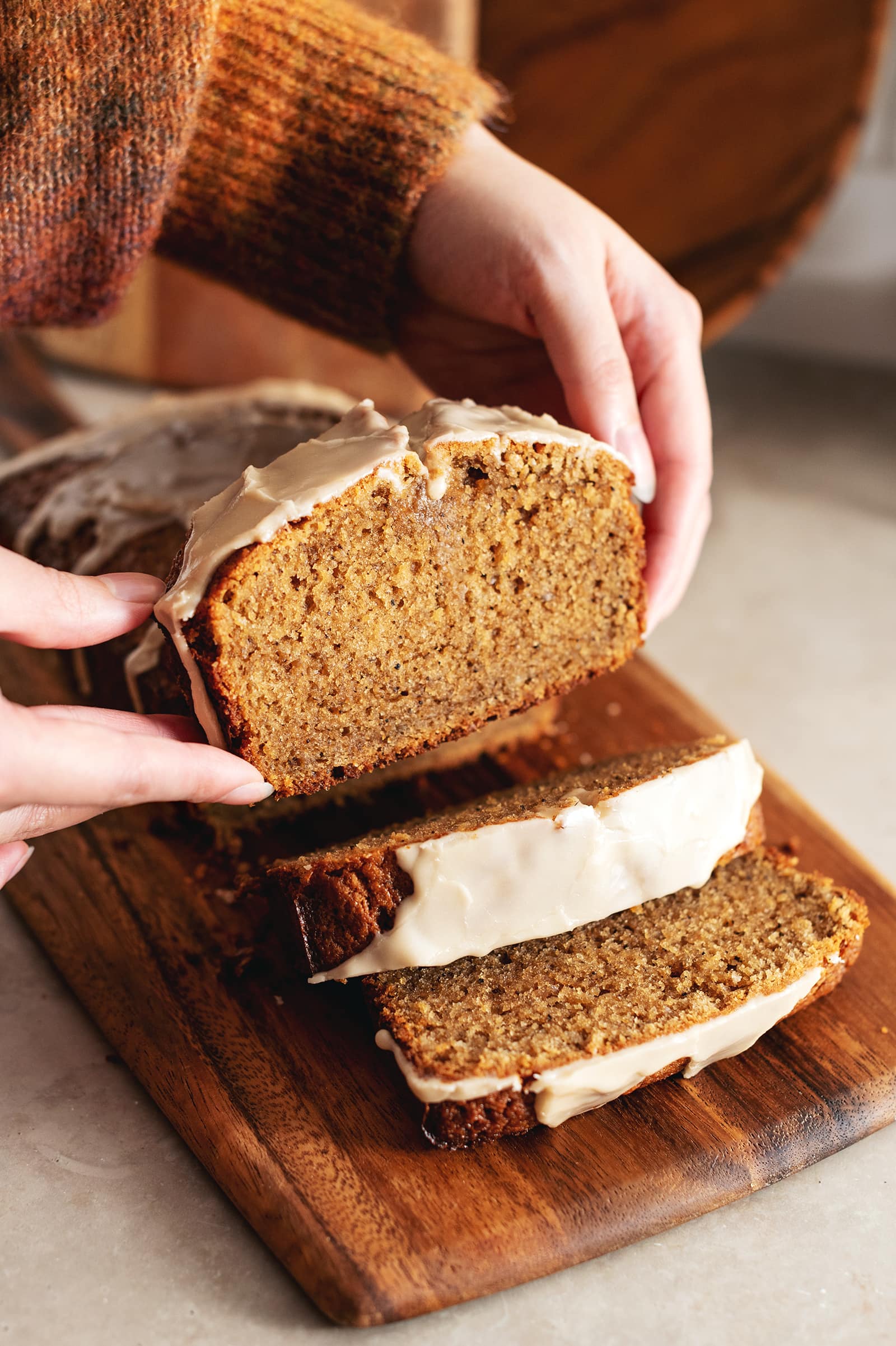Hands holding a slice of earl grey pound cake above the rest of the loaf.