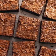 Squares of miso brownies with crackly tops scattered on parchment paper.