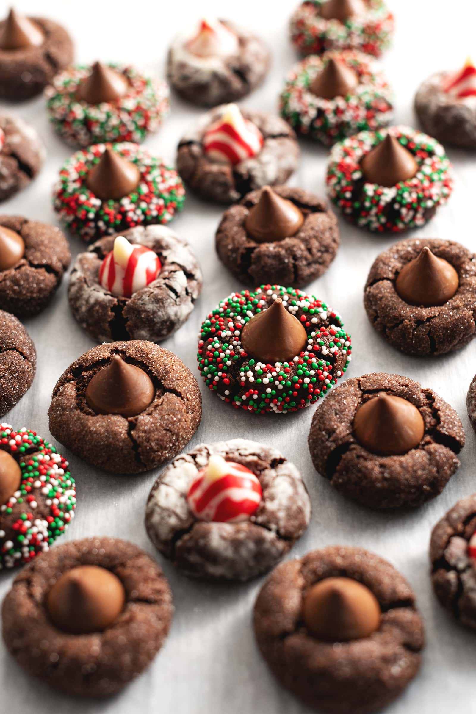 Many chocolate blossom cookies scattered on parchment paper.