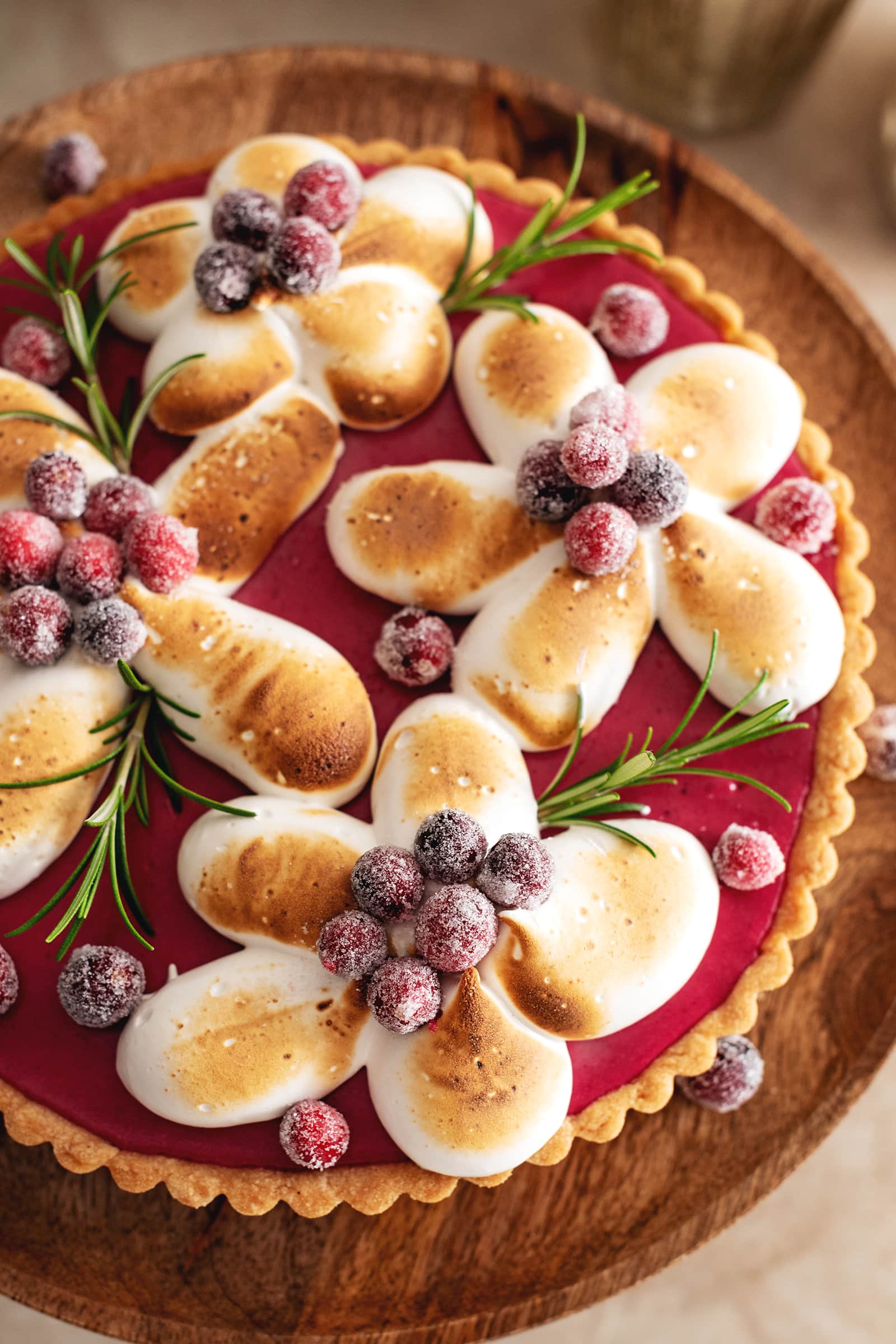 Toasted meringue piped in the shape of flowers on top of a cranberry curd tart.