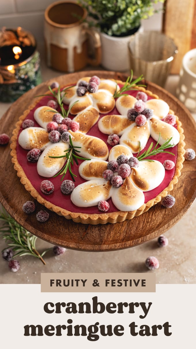 A cranberry meringue tart on a wooden cake stand.