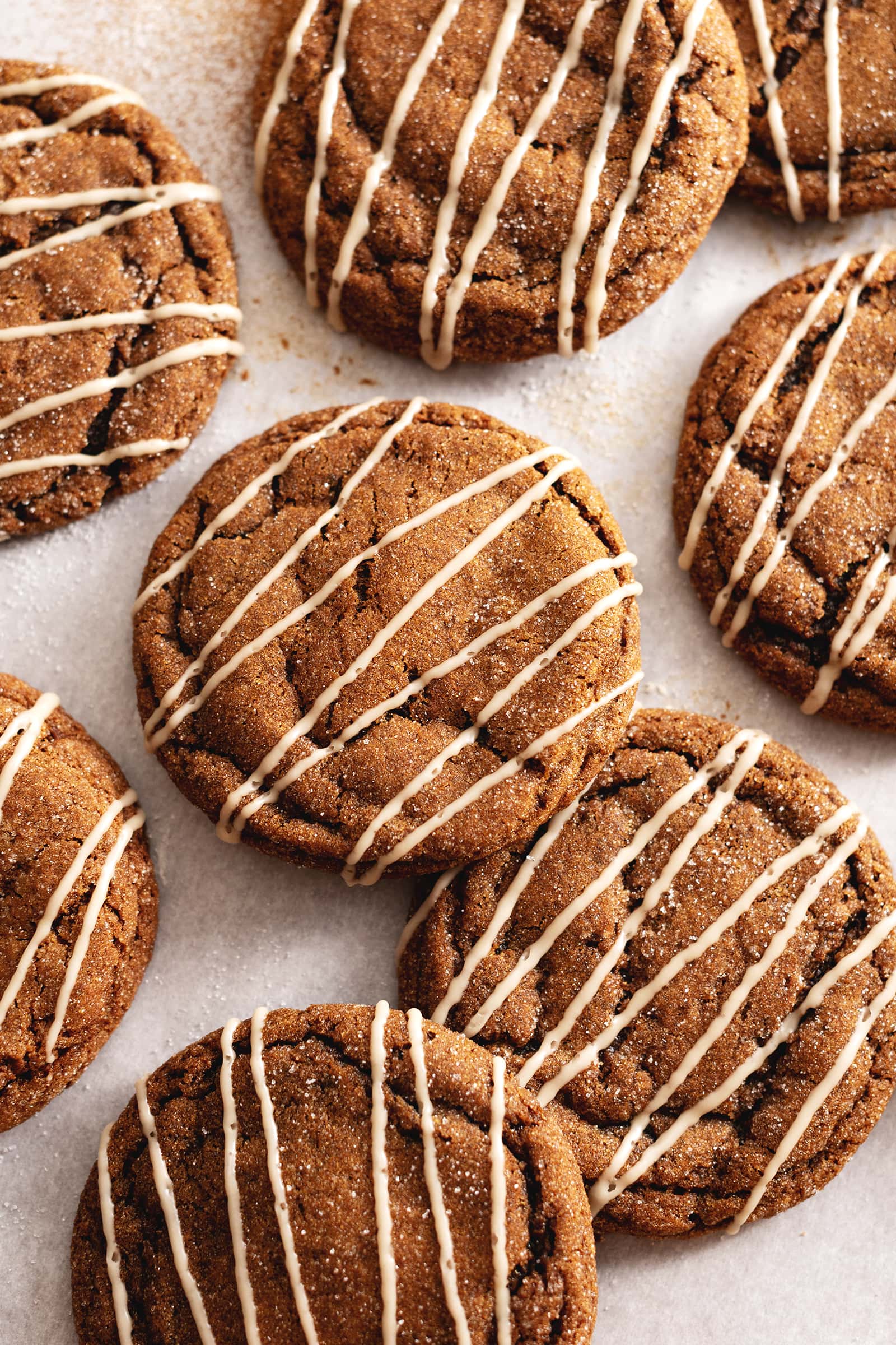 Gingerbread latte cookies drizzled with icing scattered on parchment paper.