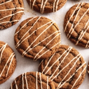 Gingerbread latte cookies drizzled with icing scattered on parchment paper.