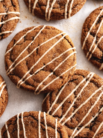 Gingerbread latte cookies drizzled with icing scattered on parchment paper.