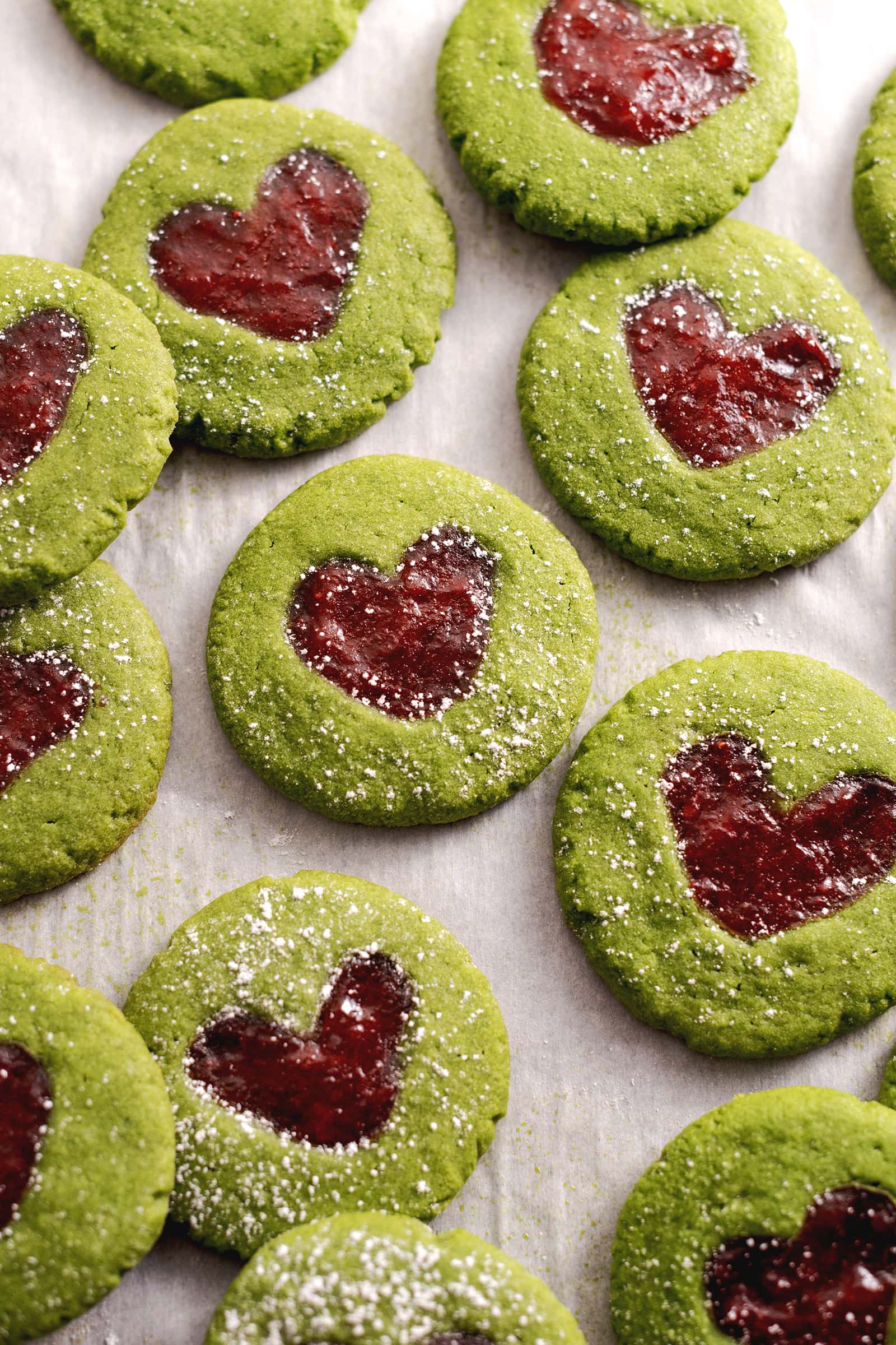 Matcha thumbprint cookies scattered on parchment paper.