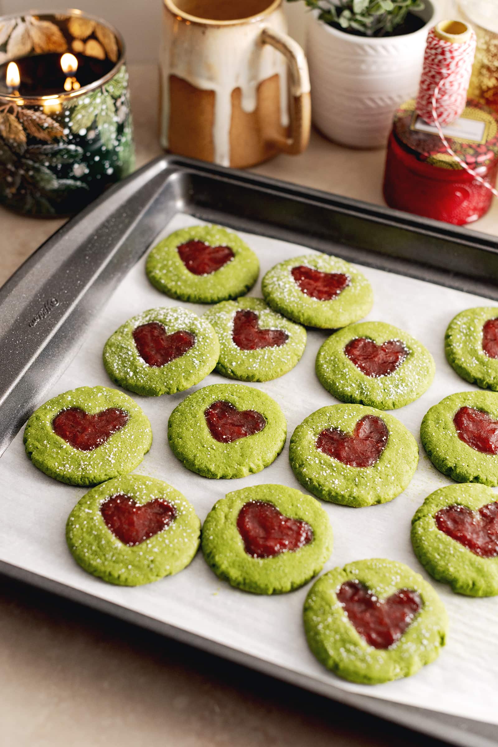 Matcha thumbprint cookies on a baking sheet on a kitchen counter.