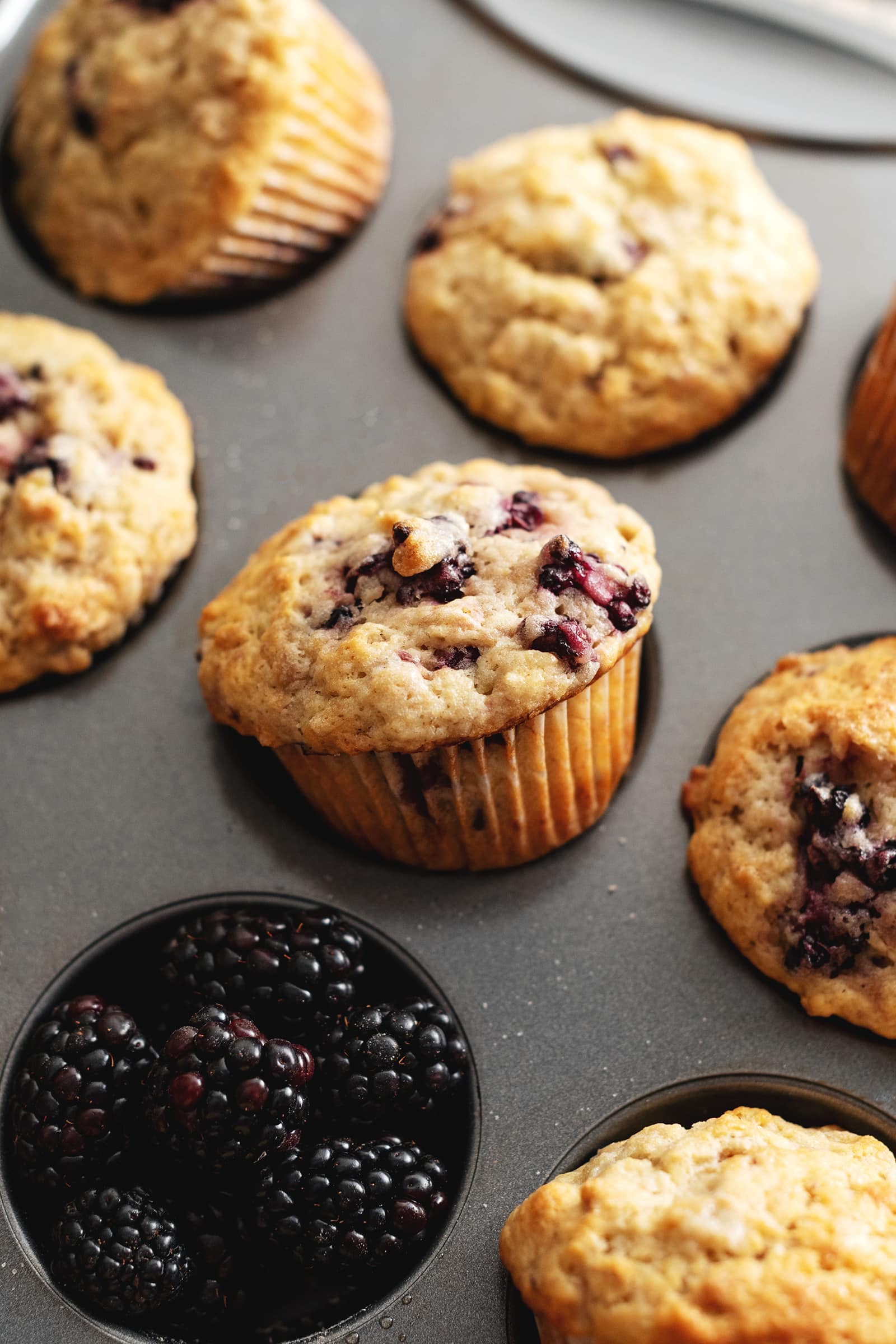 A muffin tilted out of the muffin pan to show the muffin liner.