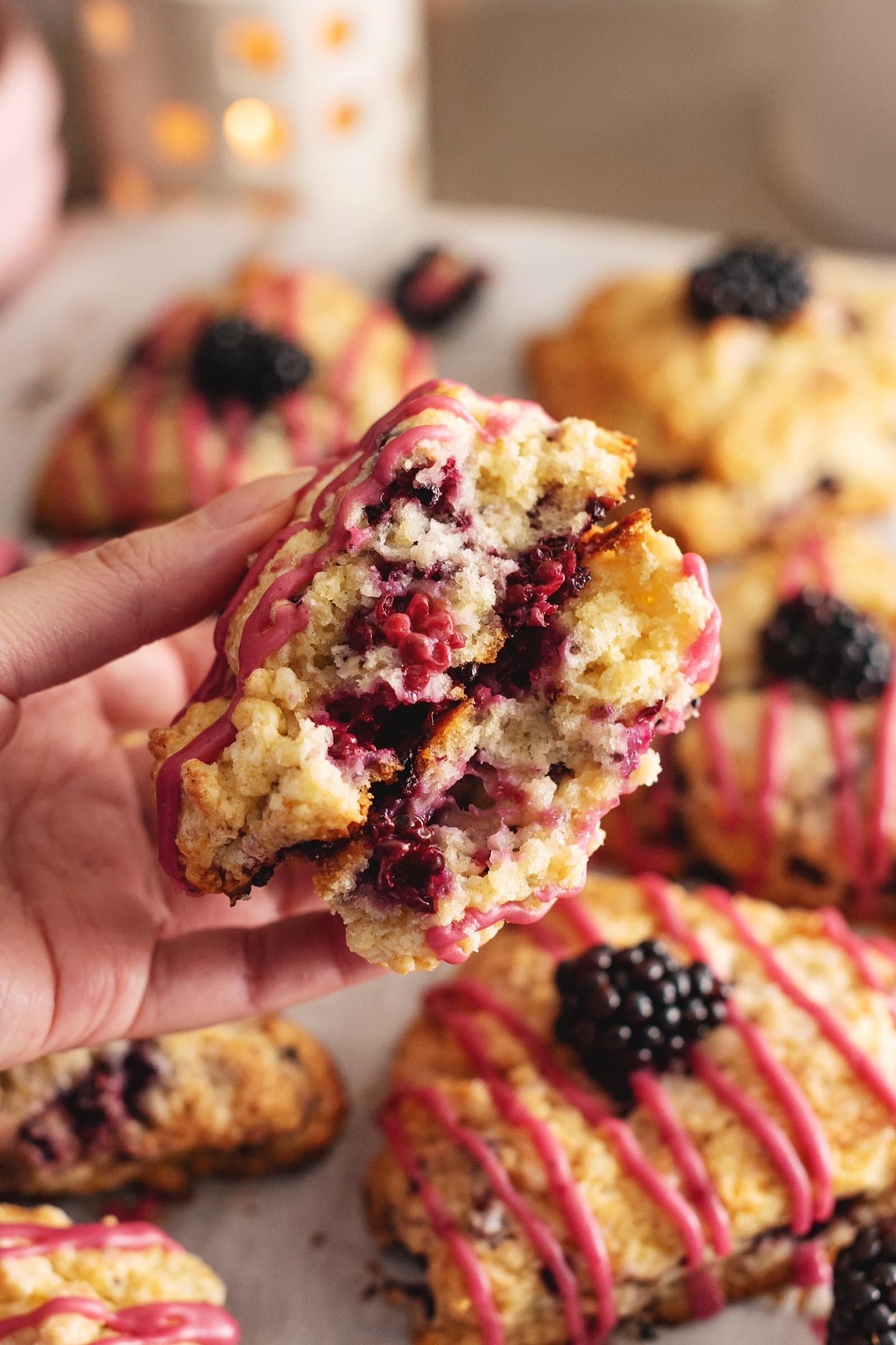 Hand holding a blackberry scone cut in half to show the fluffy texture inside.