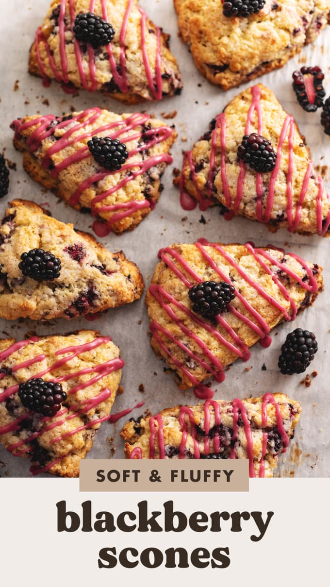 Several blackberry scones with drizzles of pink icing scattered on parchment paper.