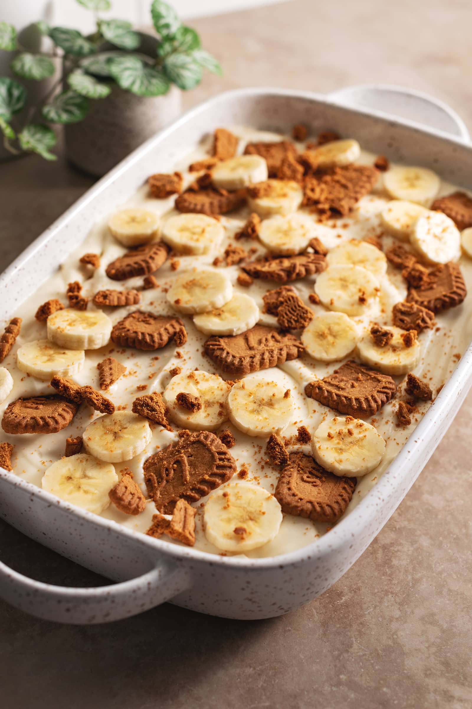 Biscoff banana pudding topped with crumbled biscoff cookies and banana slices in a large serving dish.
