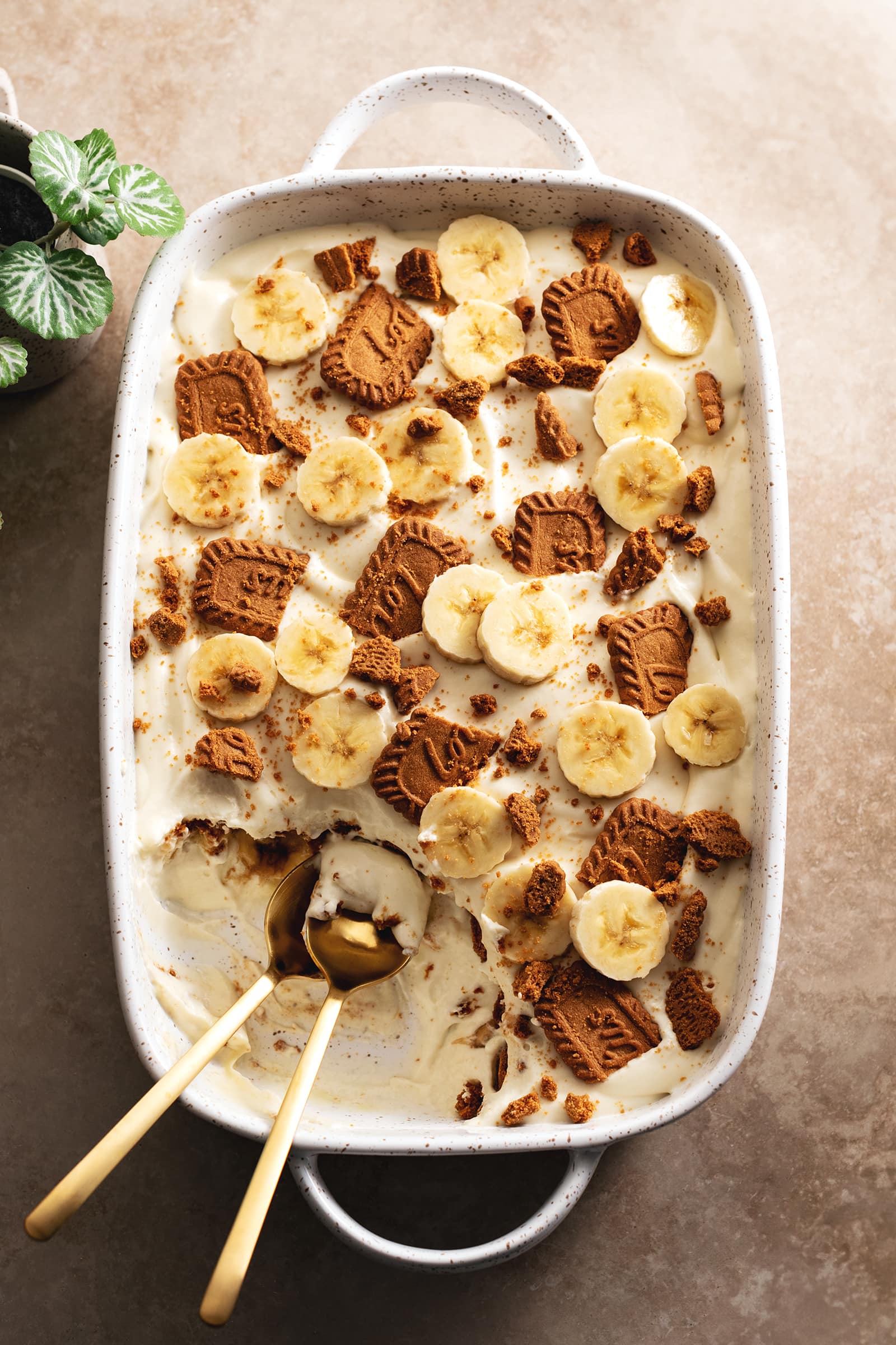 Top down view of a serving dish full of biscoff banana pudding with a corner scooped out.