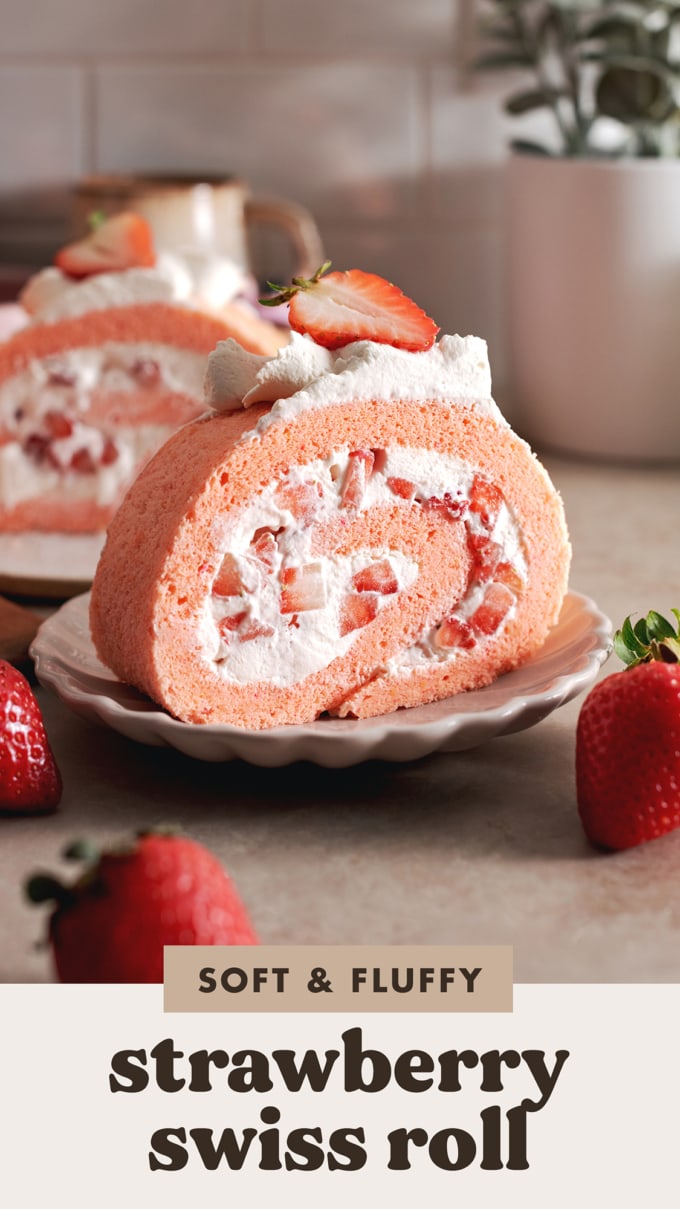 A slice of strawberry swiss roll cake rolled up with chunks of strawberries on a plate.