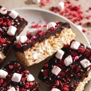 A Valentine's Day rice krispie treat leaning on its side to show the layers of chocolate ganache and rice krispies.