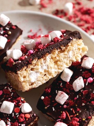 A Valentine's Day rice krispie treat leaning on its side to show the layers of chocolate ganache and rice krispies.