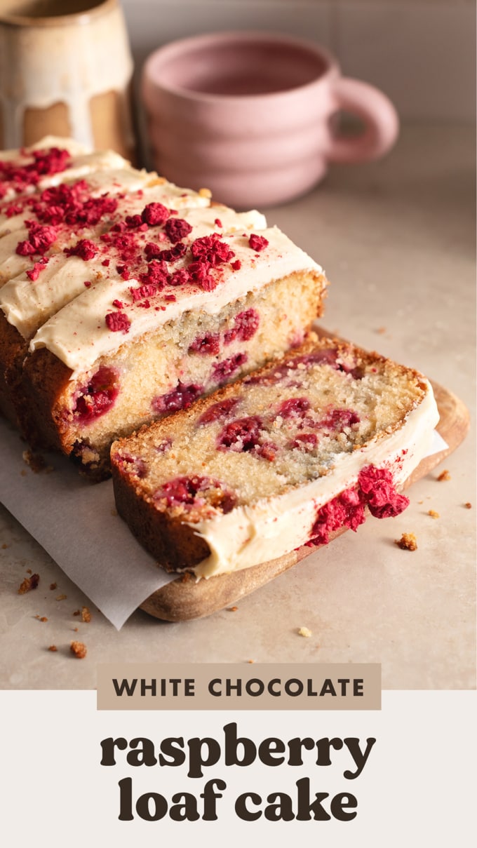 A slice of white chocolate raspberry loaf cake cut from the loaf and laying down on a wooden board.