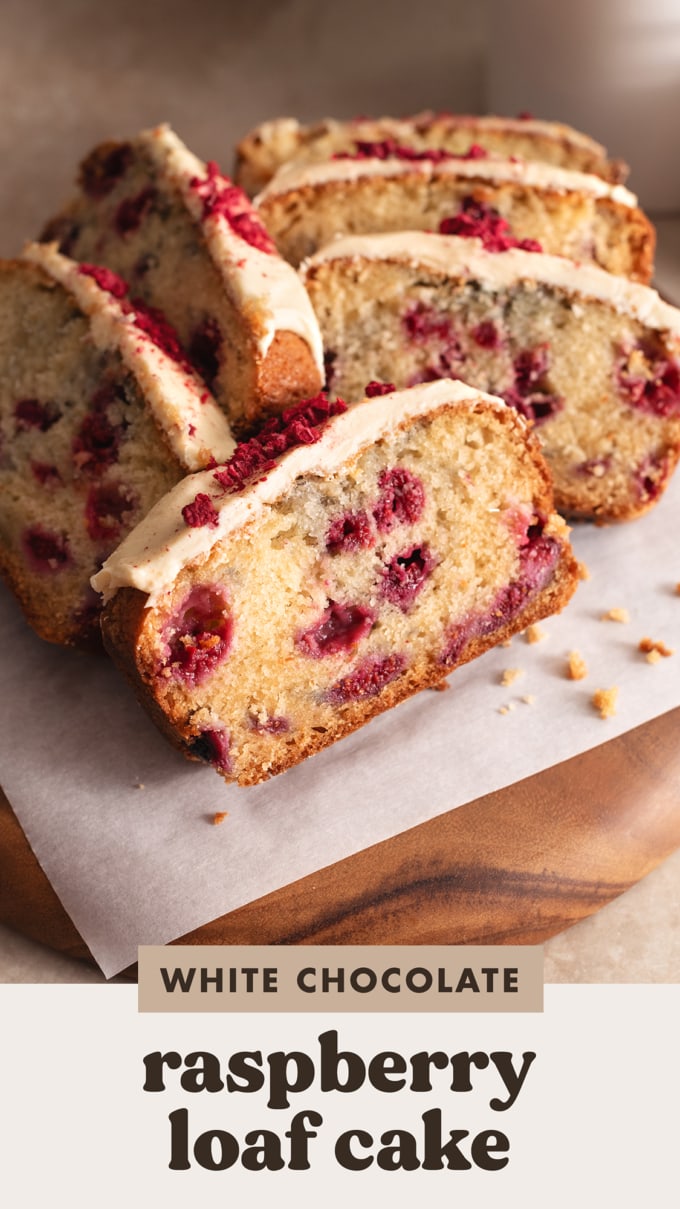 Slices of white chocolate raspberry loaf cake piled onto a wooden board.