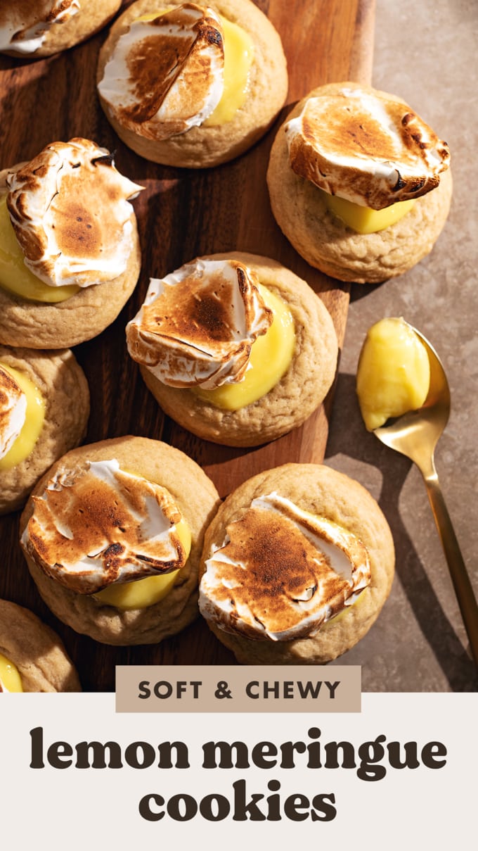Several lemon meringue cookies scattered on a wooden board next to a spoonful of lemon curd.