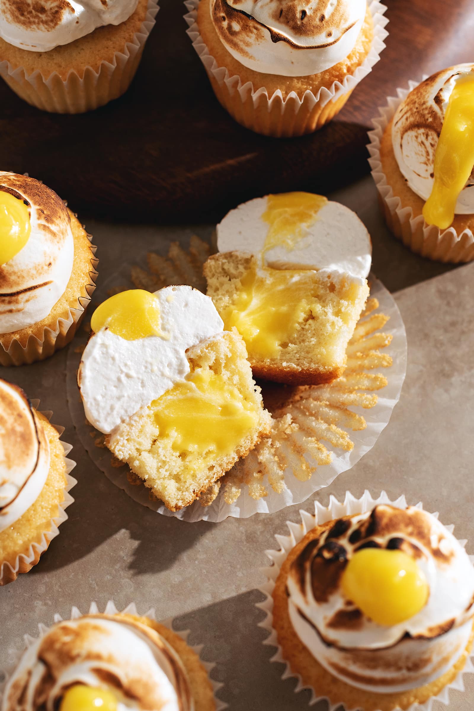 A lemon meringue cupcake cut in half to show the lemon curd filling inside.