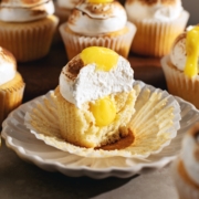 A lemon meringue cupcake cut in half to show the cross section and the lemon curd filling inside.
