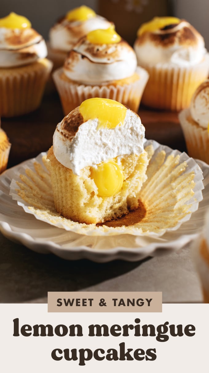 A lemon meringue cupcake cut in half to show the cross section and the lemon curd filling inside.