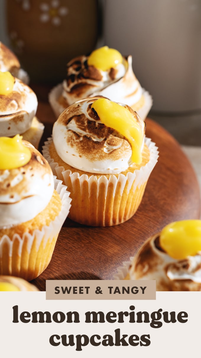 Close up of a lemon meringue cupcake with lemon curd dripping down the side of the toasted meringue.