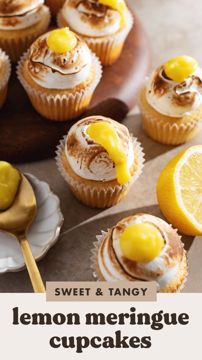 A lemon meringue cupcake with lemon curd spilling down the side surrounded by other cupcakes.
