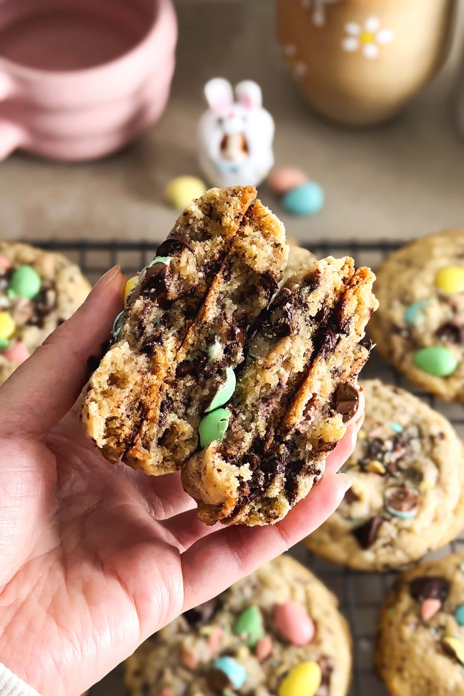 A hand holding four mini egg cookie halves to show the texture inside.