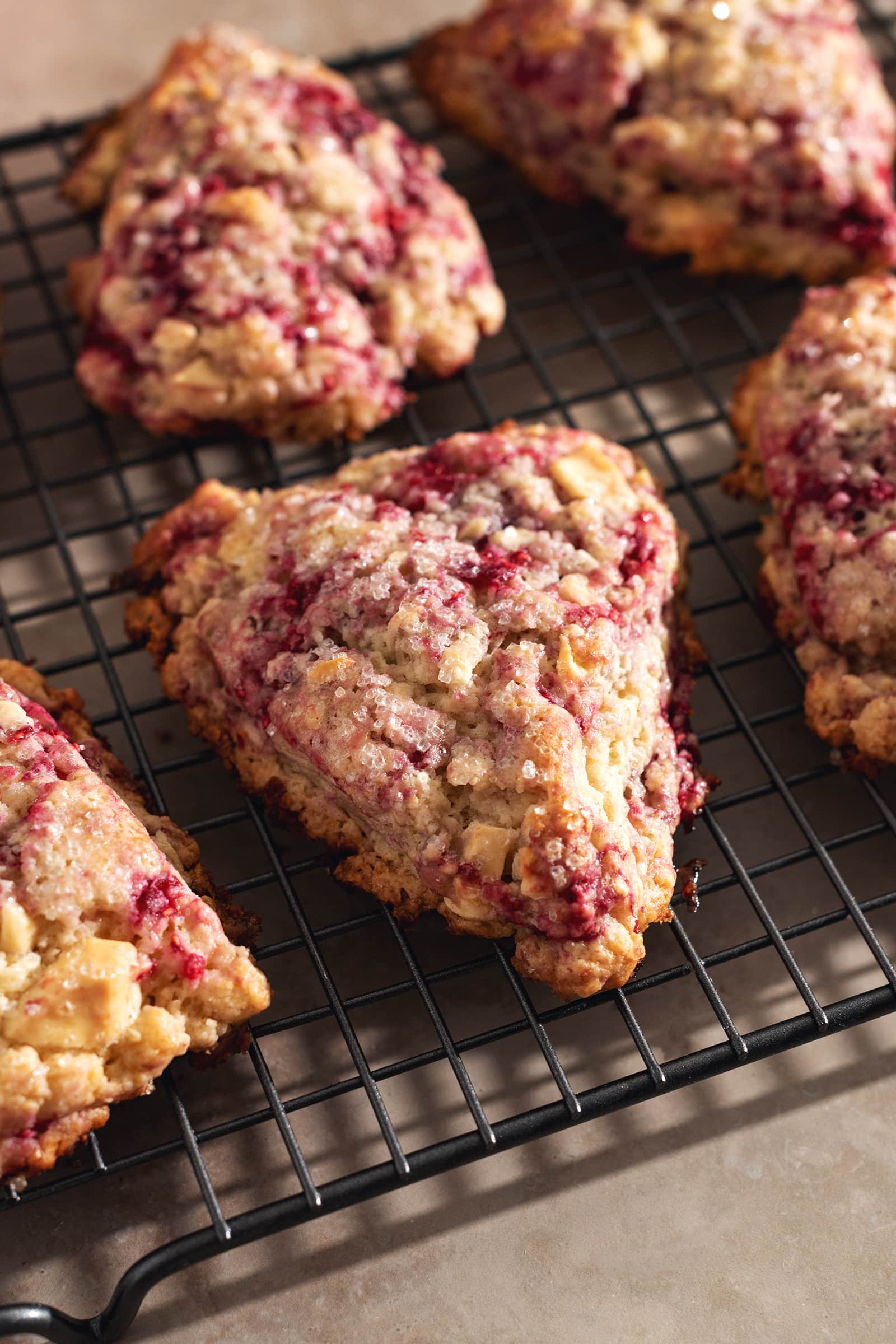White chocolate raspberry scones lined up on a wire rack.