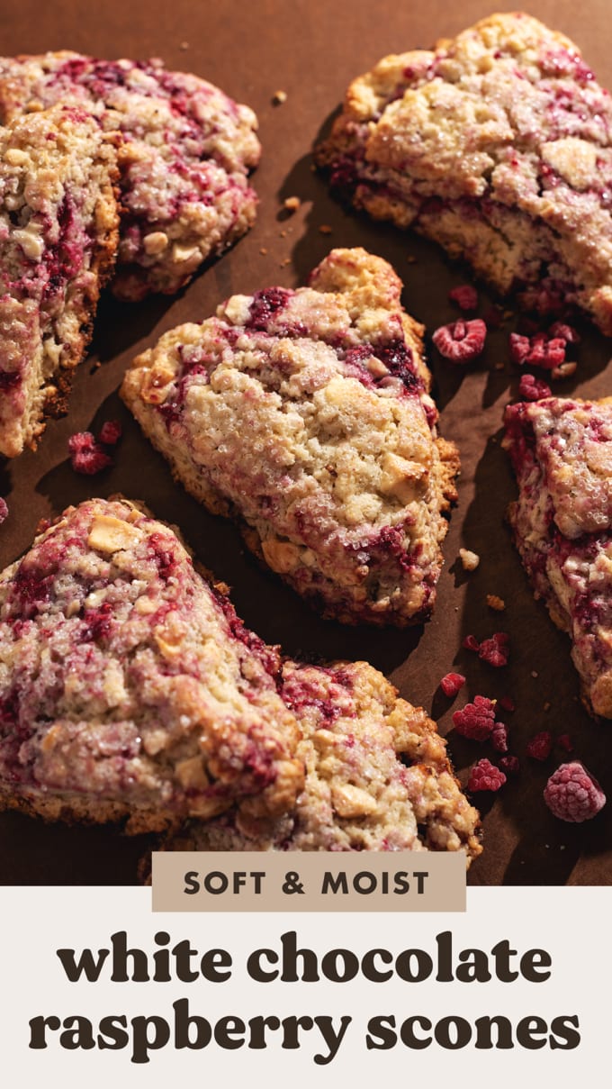 White chocolate raspberry scones scattered on a brown surface.