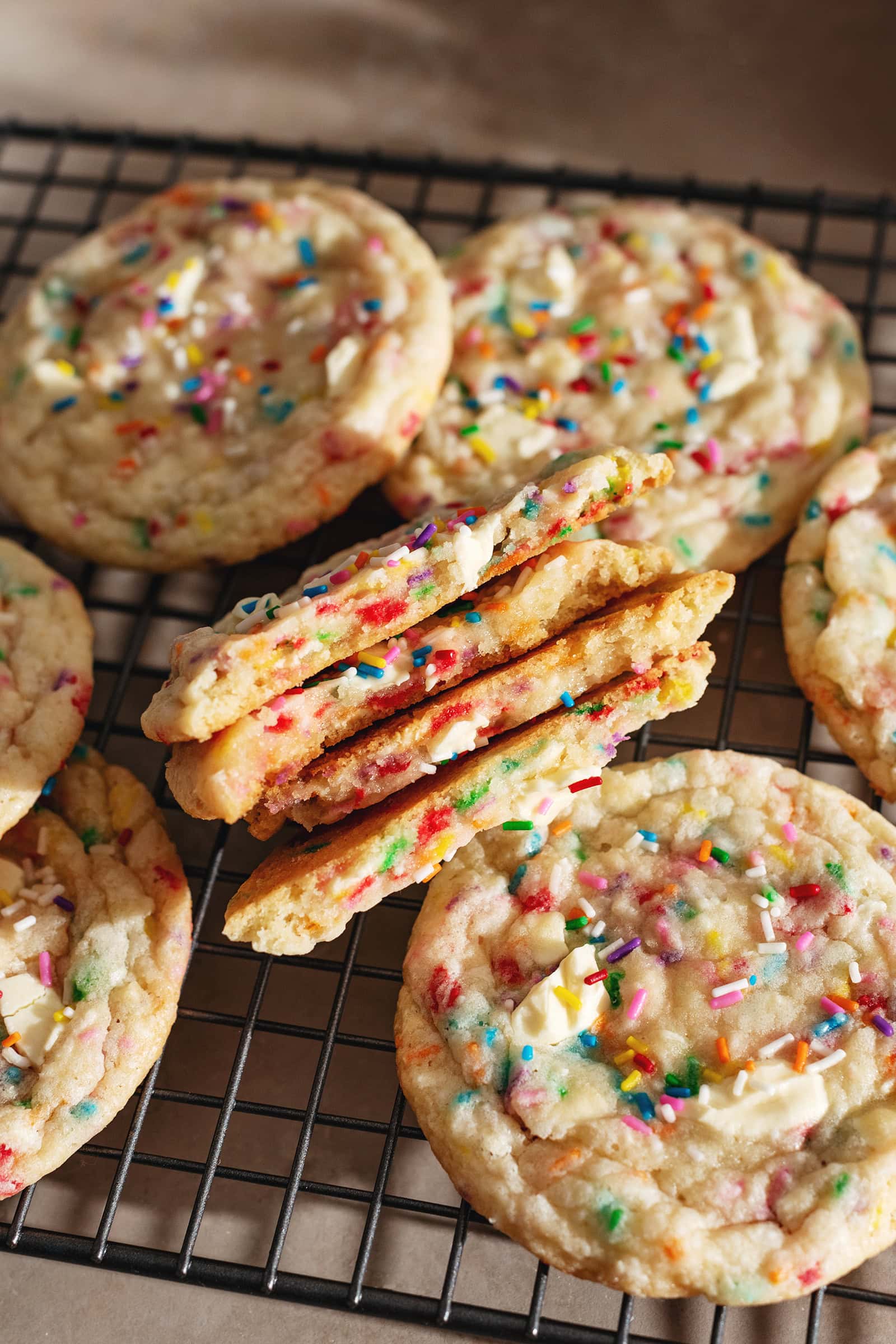 A stack of birthday cake cookies cut in half to show the texture inside.