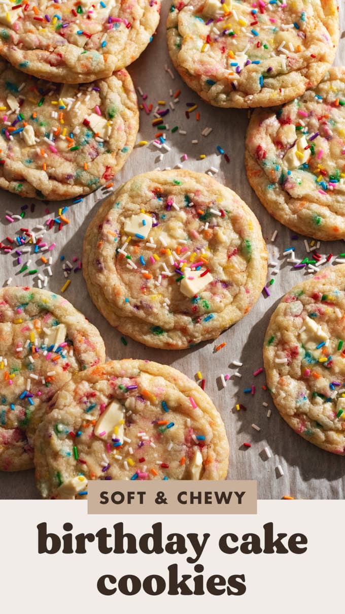 Several birthday cake cookies and rainbow sprinkles scattered on parchment paper.