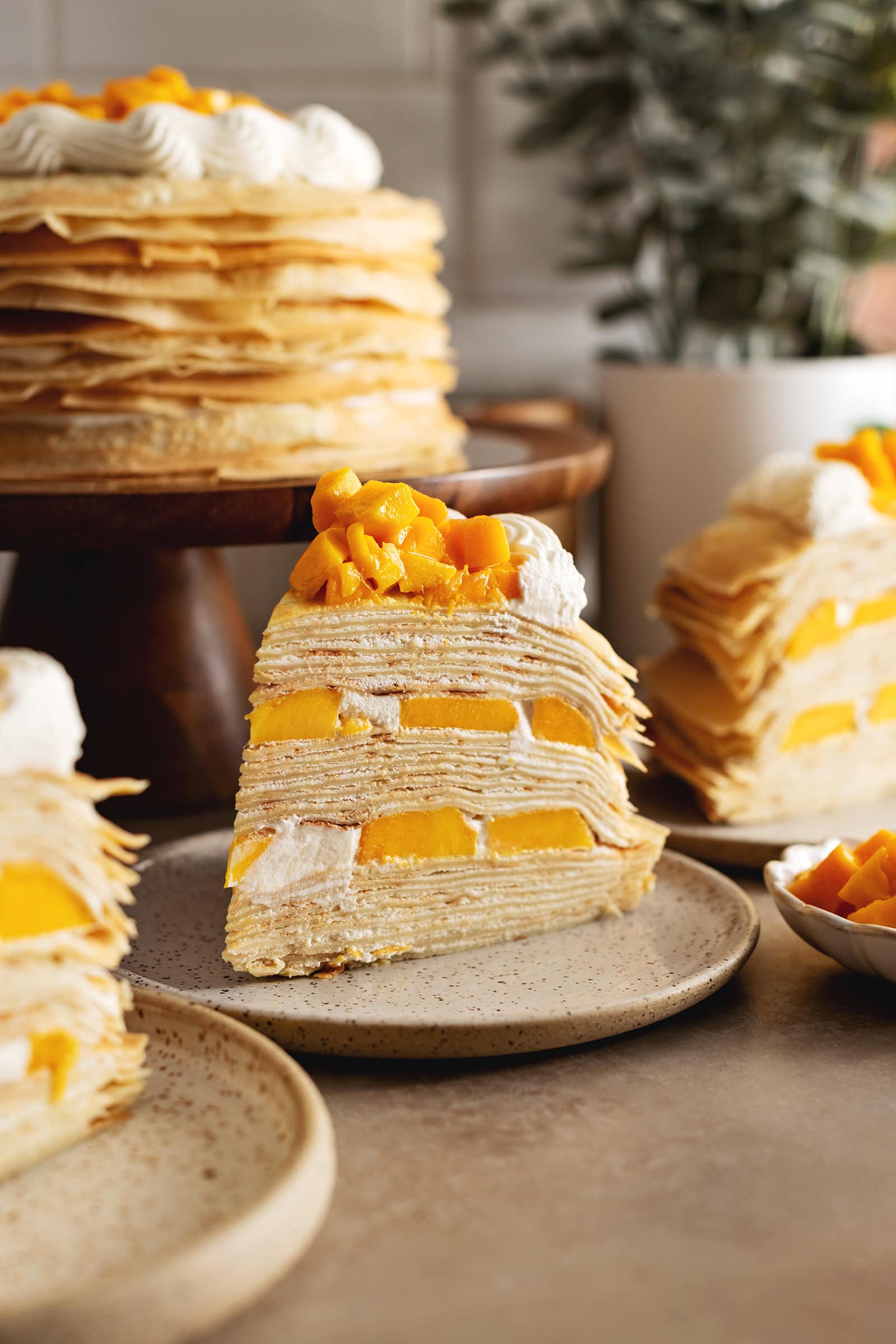 A slice of mango crepe cake on a plate showing the layers of crepes and mangoes.