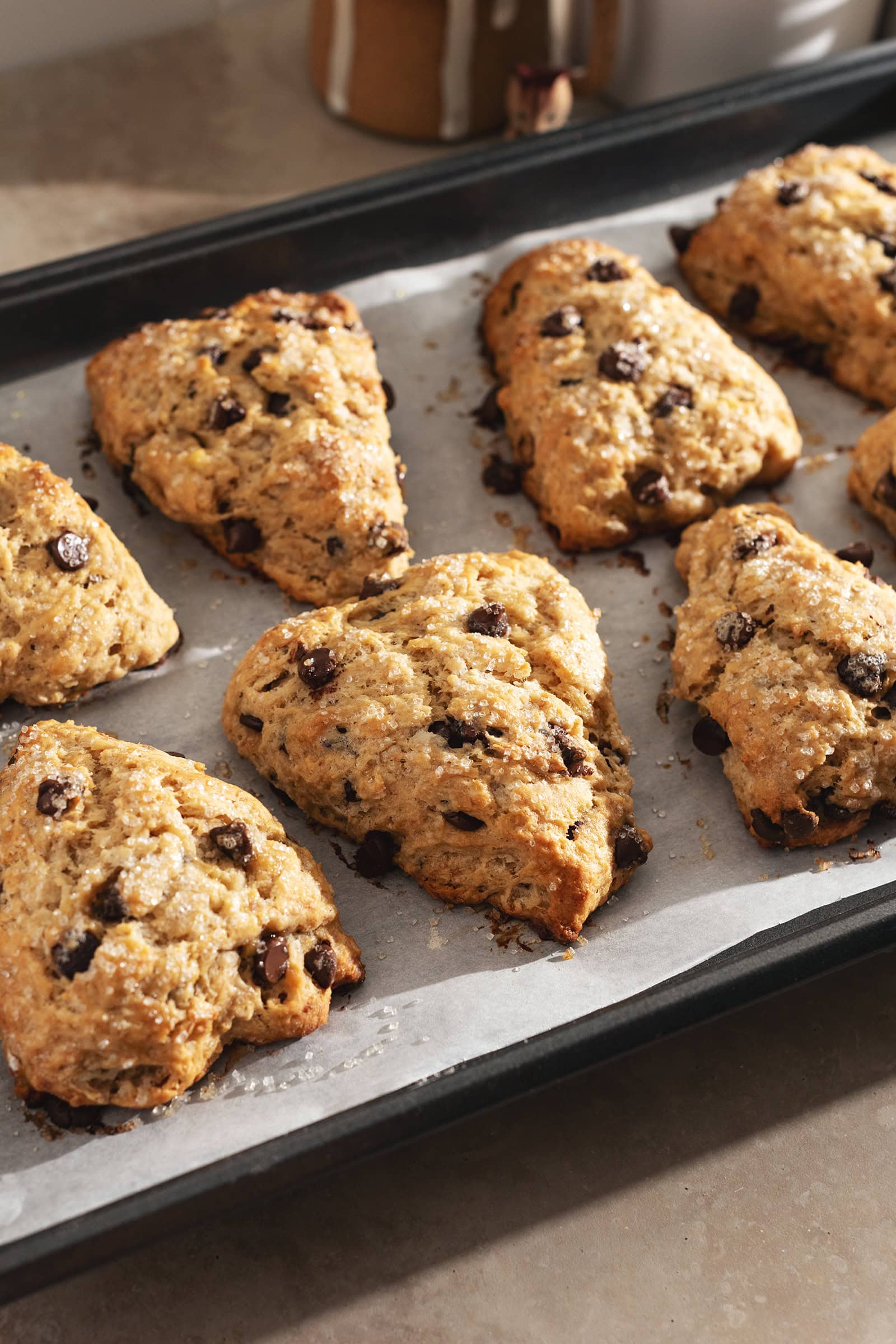 Several banana chocolate chip scones lined up on a baking tray.