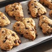 Several banana chocolate chip scones lined up on a baking tray.