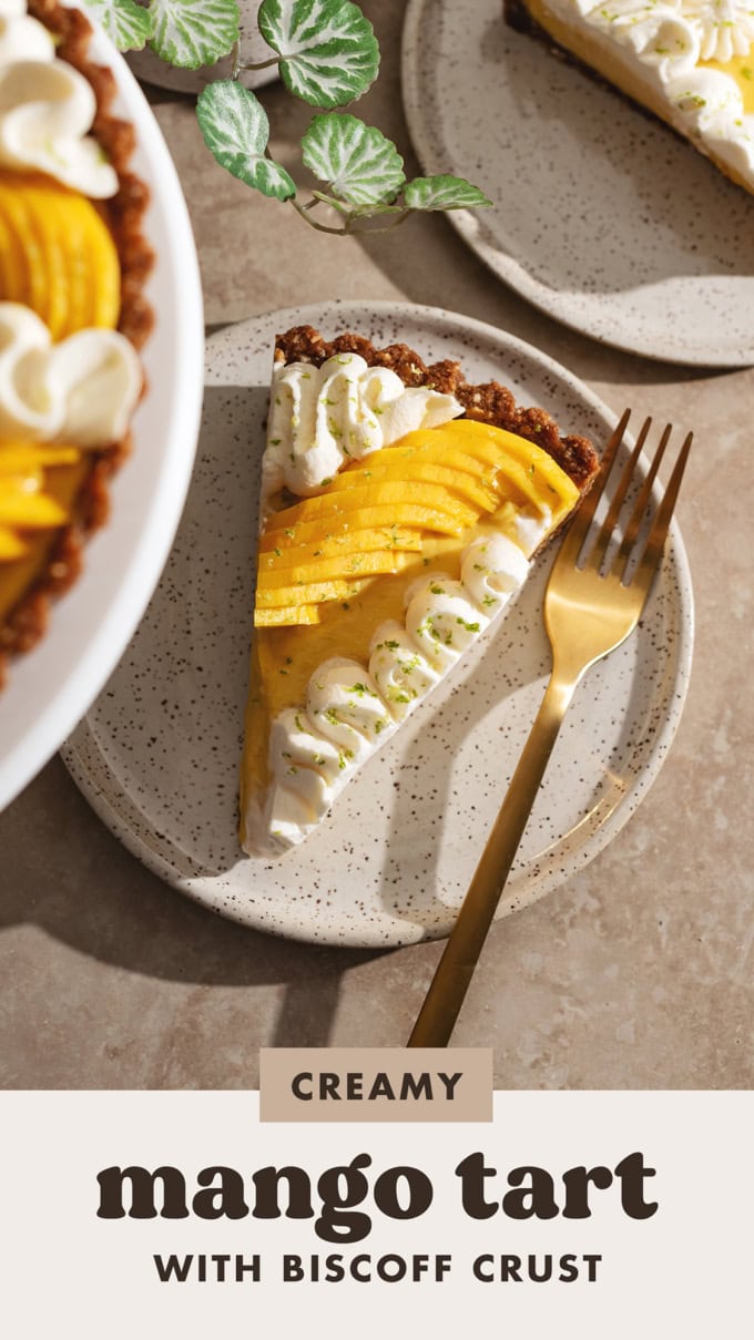 A slice of mango tart on a plate with a fork and the rest of the tart blurred in the foreground.