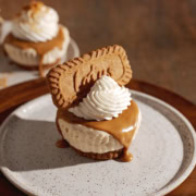 A mini biscoff cheesecake on a plate with biscoff spread dripping down the side.