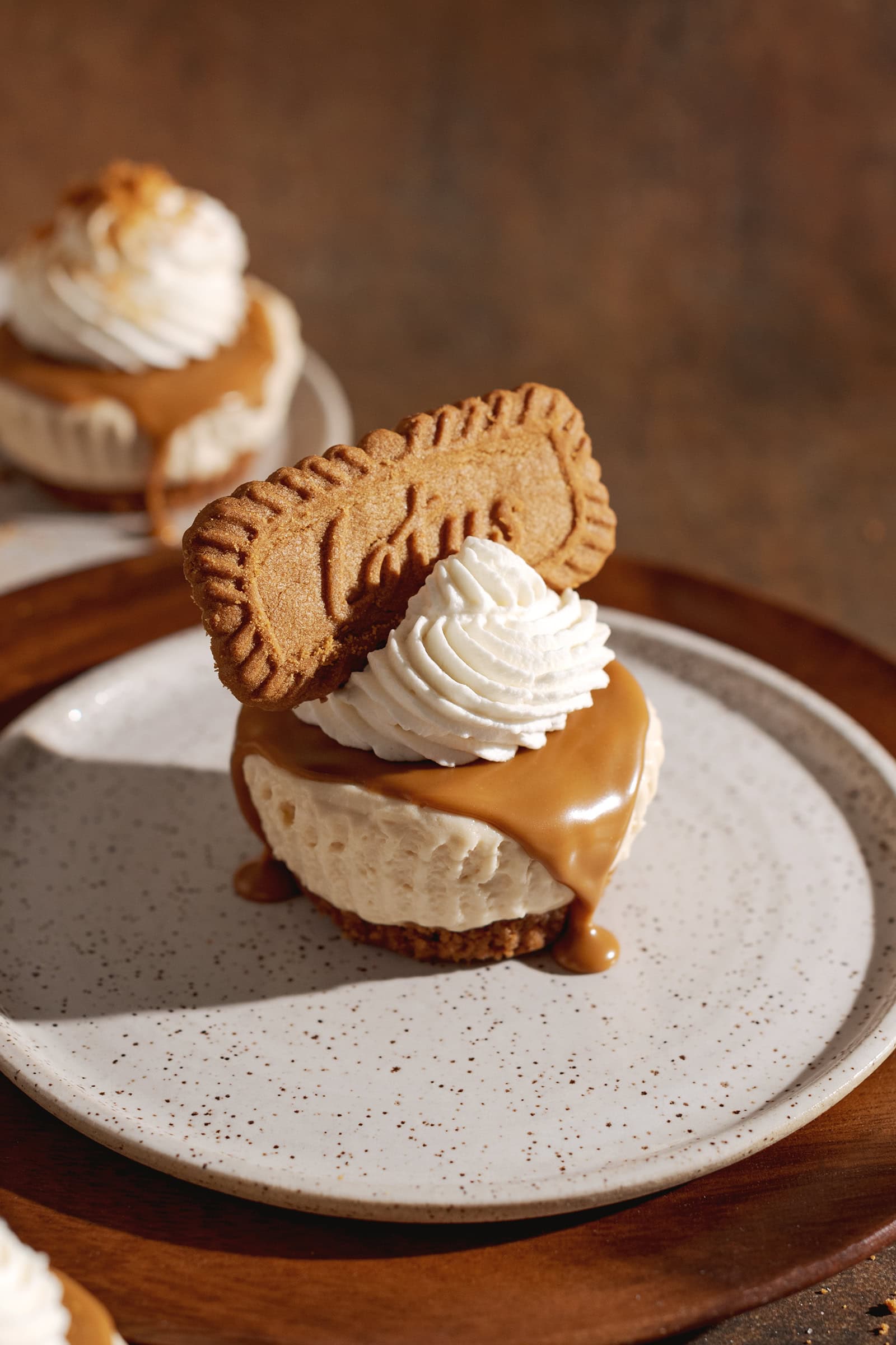 A mini biscoff cheesecake on a plate with biscoff spread dripping down the side.