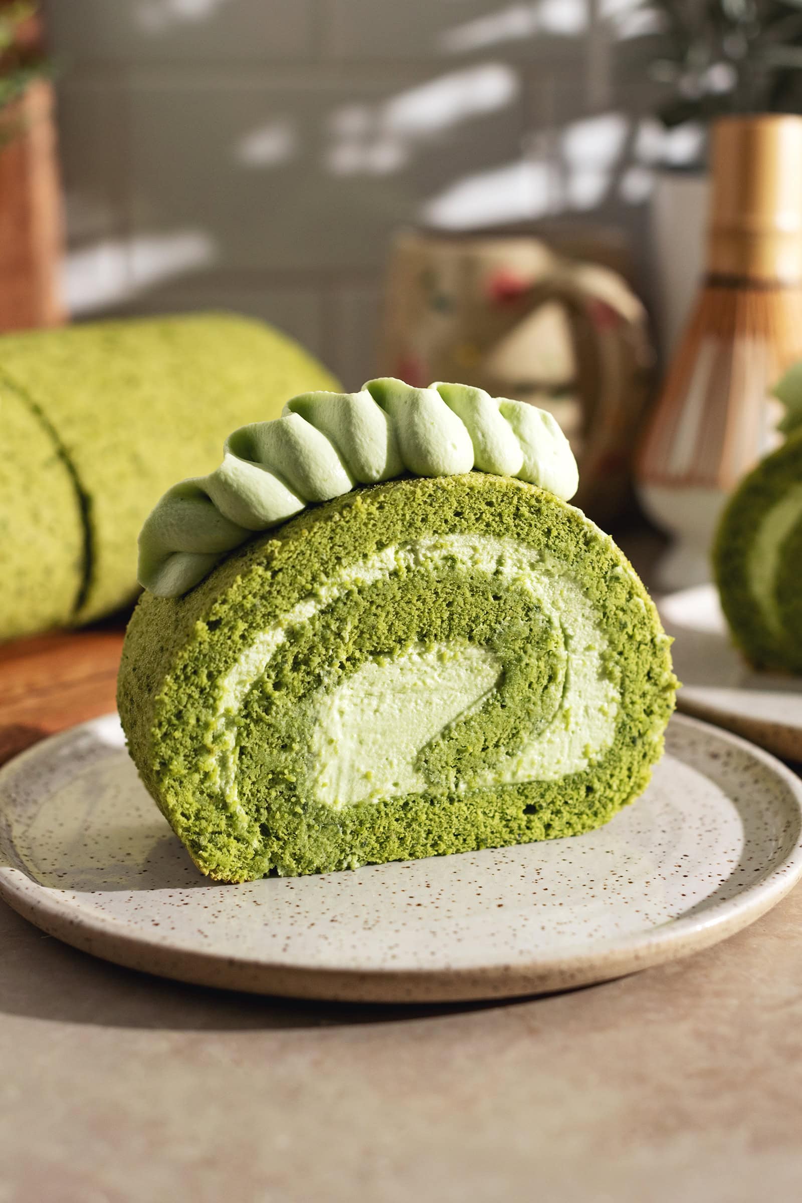 A slice of matcha roll cake on a plate showing a perfect swirl.