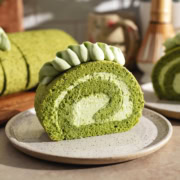 A slice of matcha roll cake on a plate showing a perfect swirl.