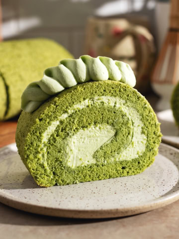 A slice of matcha roll cake on a plate showing a perfect swirl.