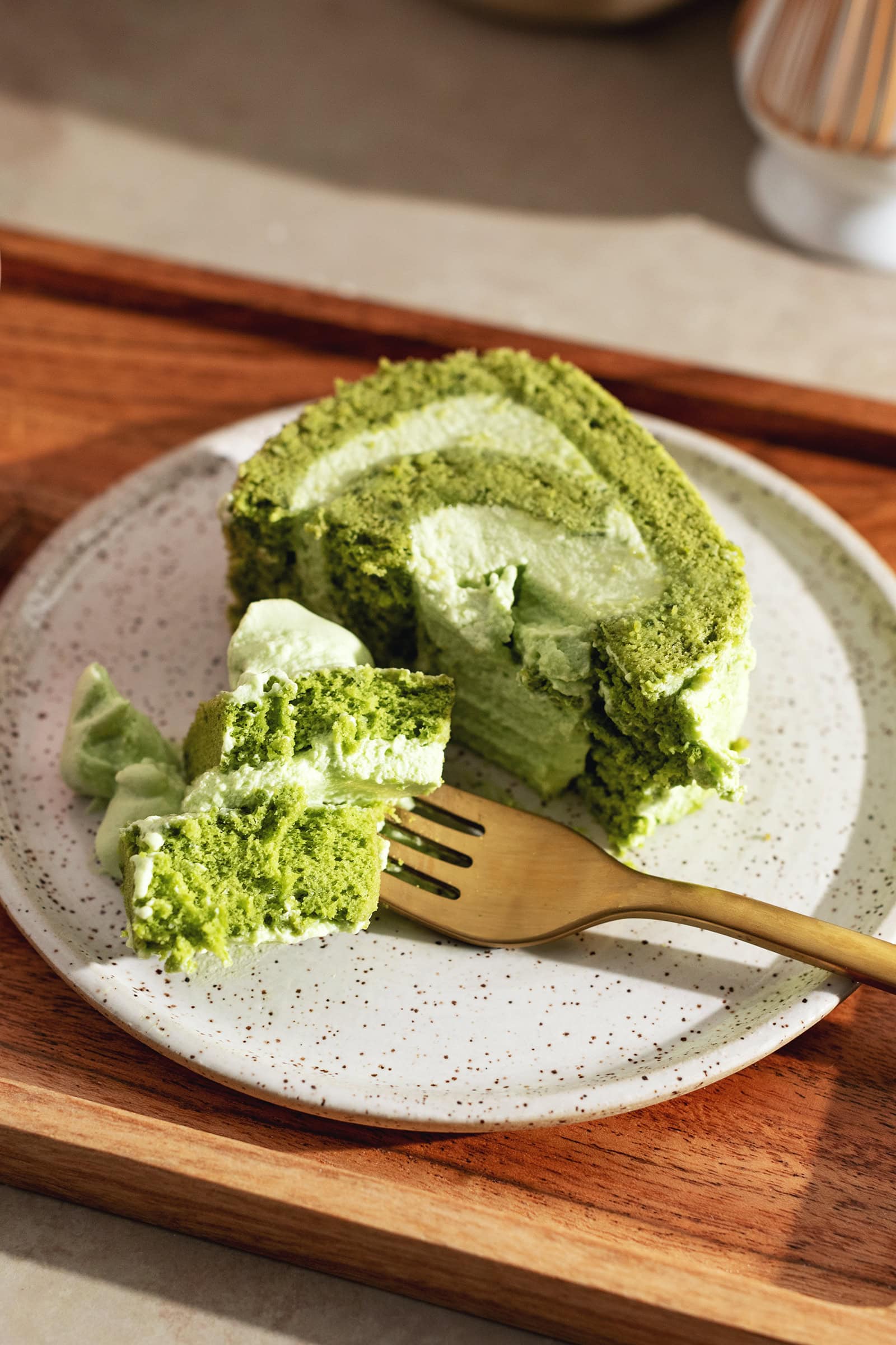 A forkful of matcha cake on a plate with the rest of the slice.