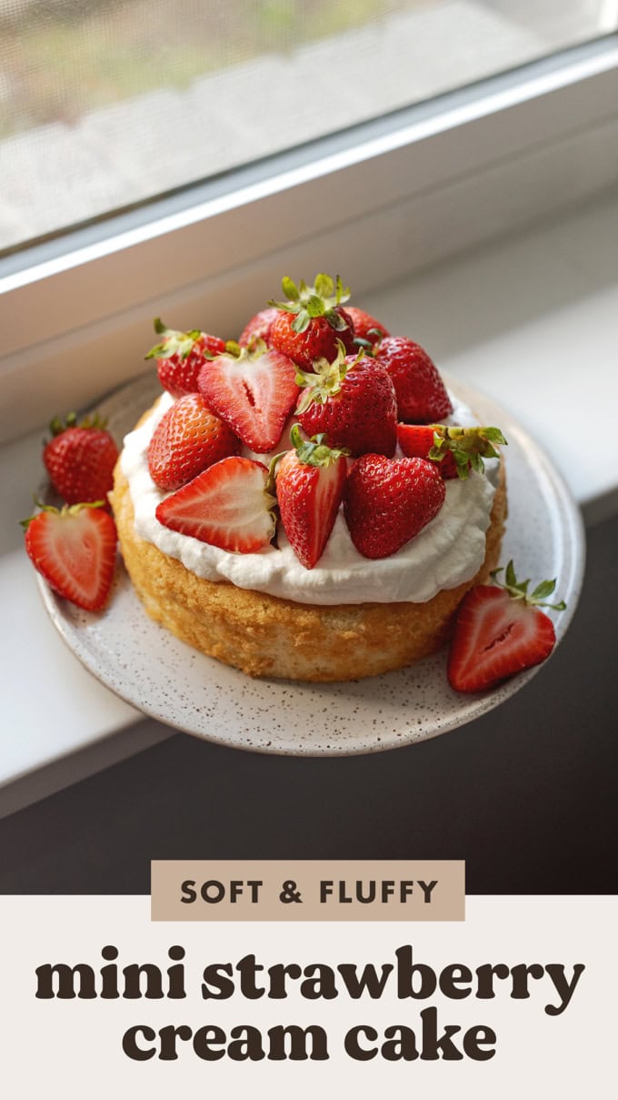 A strawberry cake on a plate placed on a windowsill.