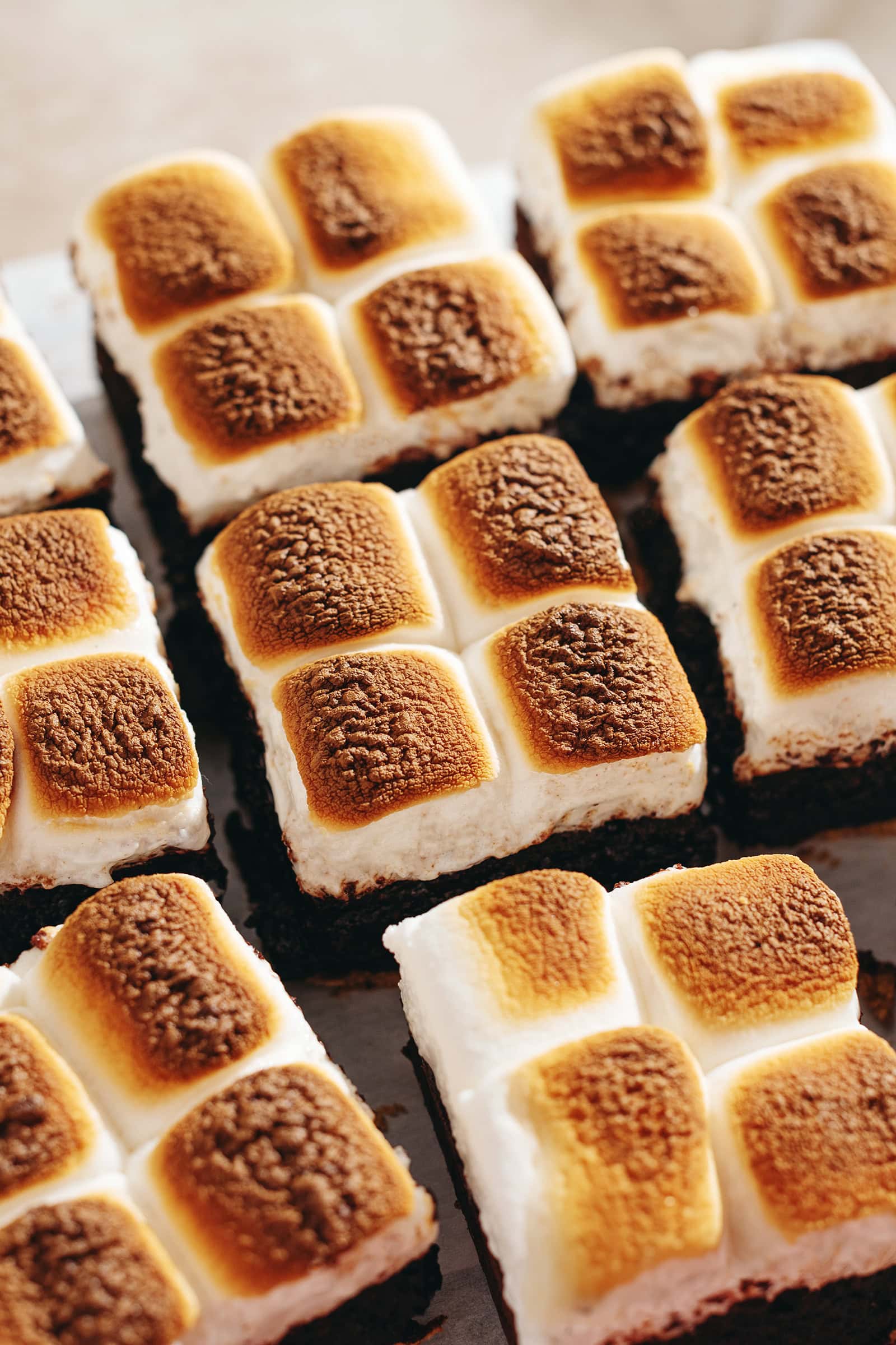 S'mores brownies lined up side by side with toasted marshmallows on top.
