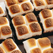 S'mores brownies lined up side by side with toasted marshmallows on top.