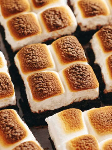 S'mores brownies lined up side by side with toasted marshmallows on top.